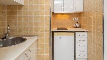 A compact kitchen with a sink, dishwasher, and white cabinets.