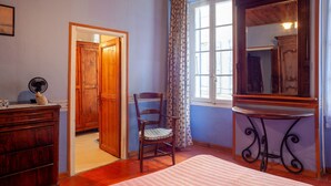 A room with a wooden ceiling, a chair, a table with a mirror, a window with curtains, and a door leading to another room. - Holiday Home 'Maison À Sigean' with Wi-Fi (Sigean)