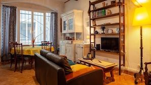 A living room with a sofa, dining table, chairs, a TV, and a bookshelf. - Holiday Home 'Maison À Sigean' with Wi-Fi (Sigean)