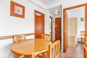 A dining area with a wooden table and chairs, a wooden door, and a light-colored wall.