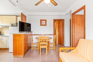 A compact living space with a kitchenette, a dining area with a table and chairs, and a sofa.