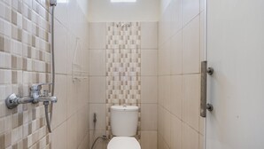 Um banheiro pequeno com azulejos, chuveiro, vaso sanitário e janela.