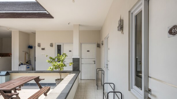 Uma cozinha limpa e moderna, com geladeira embutida, uma mesa de madeira e um vaso com planta.