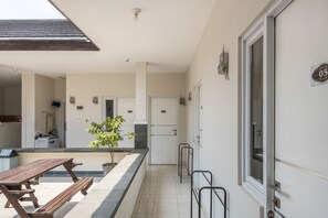 A clean, modern kitchen with a built-in refrigerator, a wooden table, and a potted plant. - OYO Living 1877 Side Corner (West Cirebon)