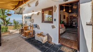 A stone-walled building with a wooden balcony, a dining area, and a view of the sea. - Vacation Home 'Land Of Dreams' with Sea View, Shared Pool and Wi-Fi (Cruz de tea)