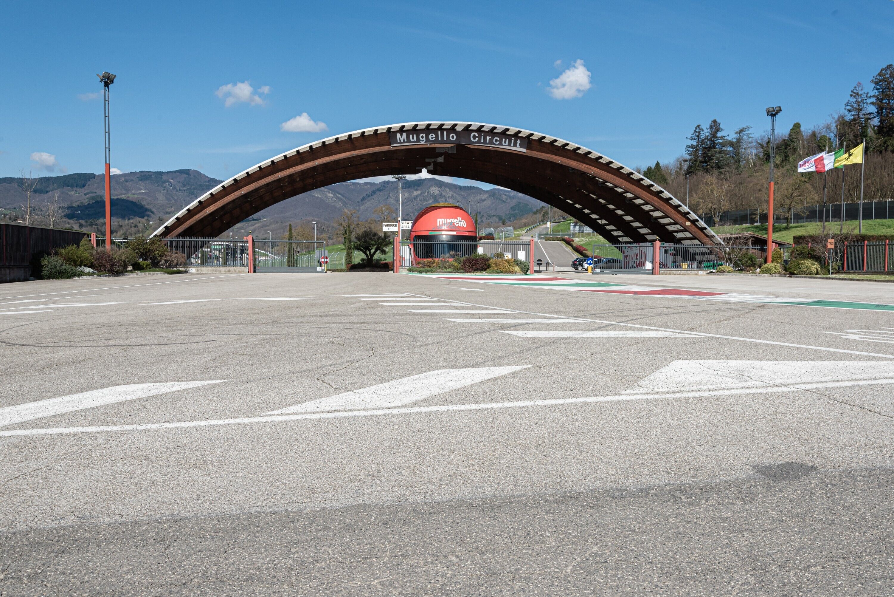 Une arche portant l’inscription « Mugello Circuit », avec une piste de course au premier plan et des montagnes en arrière-plan.