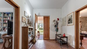 Een ruime woonkamer met een boekenkast, een televisie, een eettafel en een keuken, zichtbaar door een open deur.