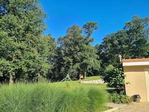 Ein Garten mit Spielplatz, einer Steinmauer und einem Gebäude mit Ziegeldach.