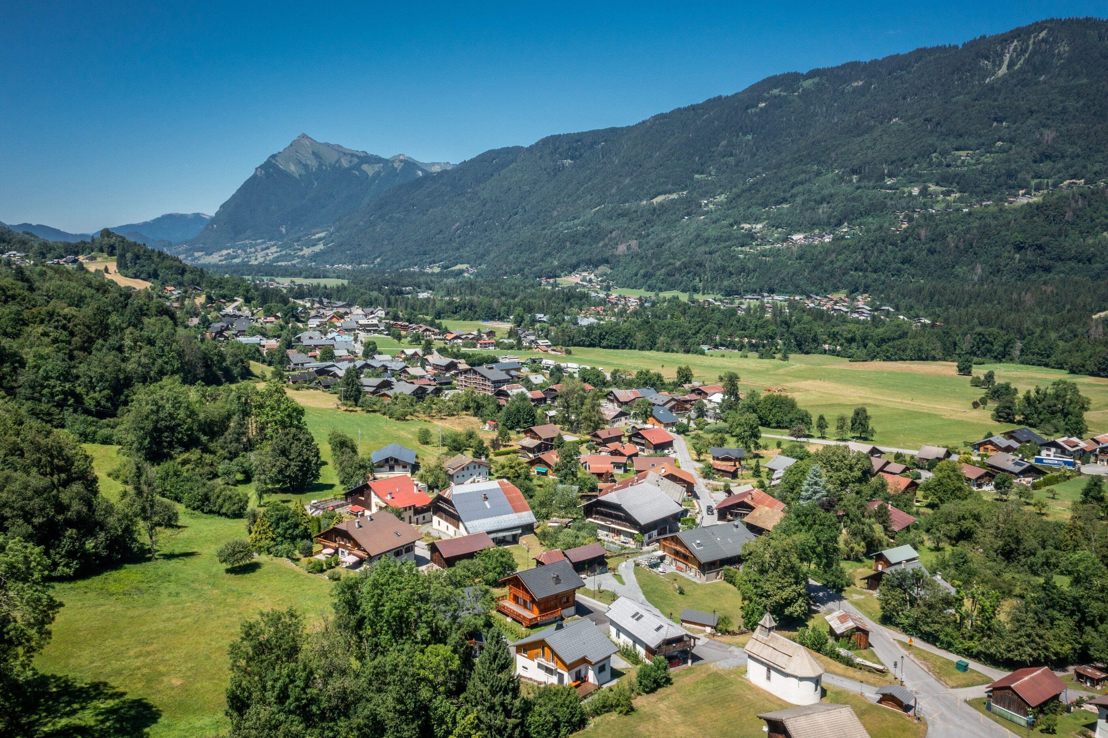 A mountainous village with houses, roads, and green fields.