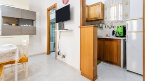 Een kleine keuken met houten kastjes, een ingebouwde televisie en een koelkast.