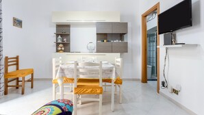 Een eetruimte met een tafel, stoelen en een aan de muur bevestigde televisie.