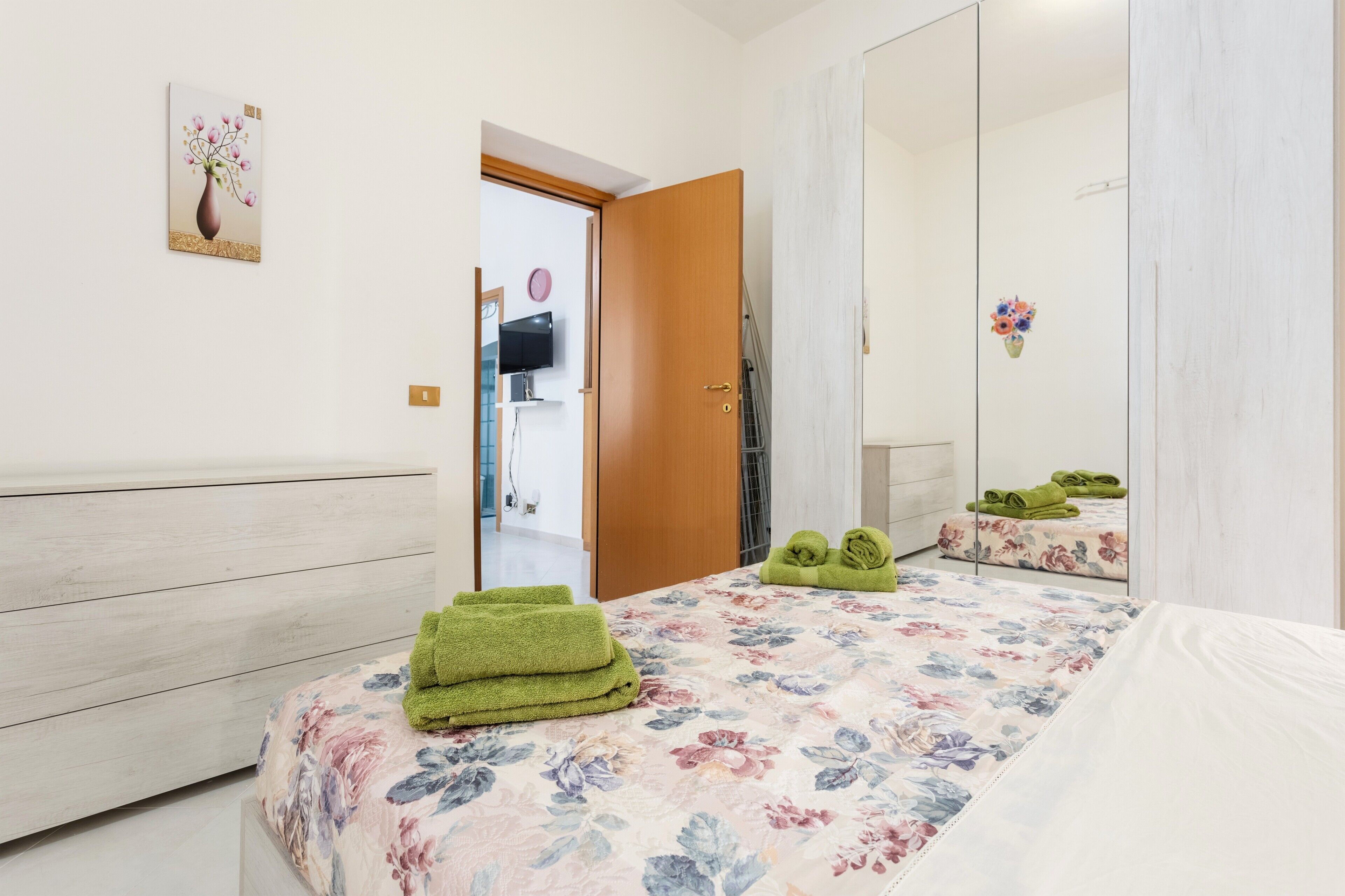 A bedroom with a bed, a wardrobe, a mirror, and a door leading to a bathroom.