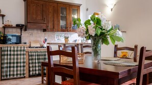 A dining area with a wooden table, chairs, and a vase with flowers.