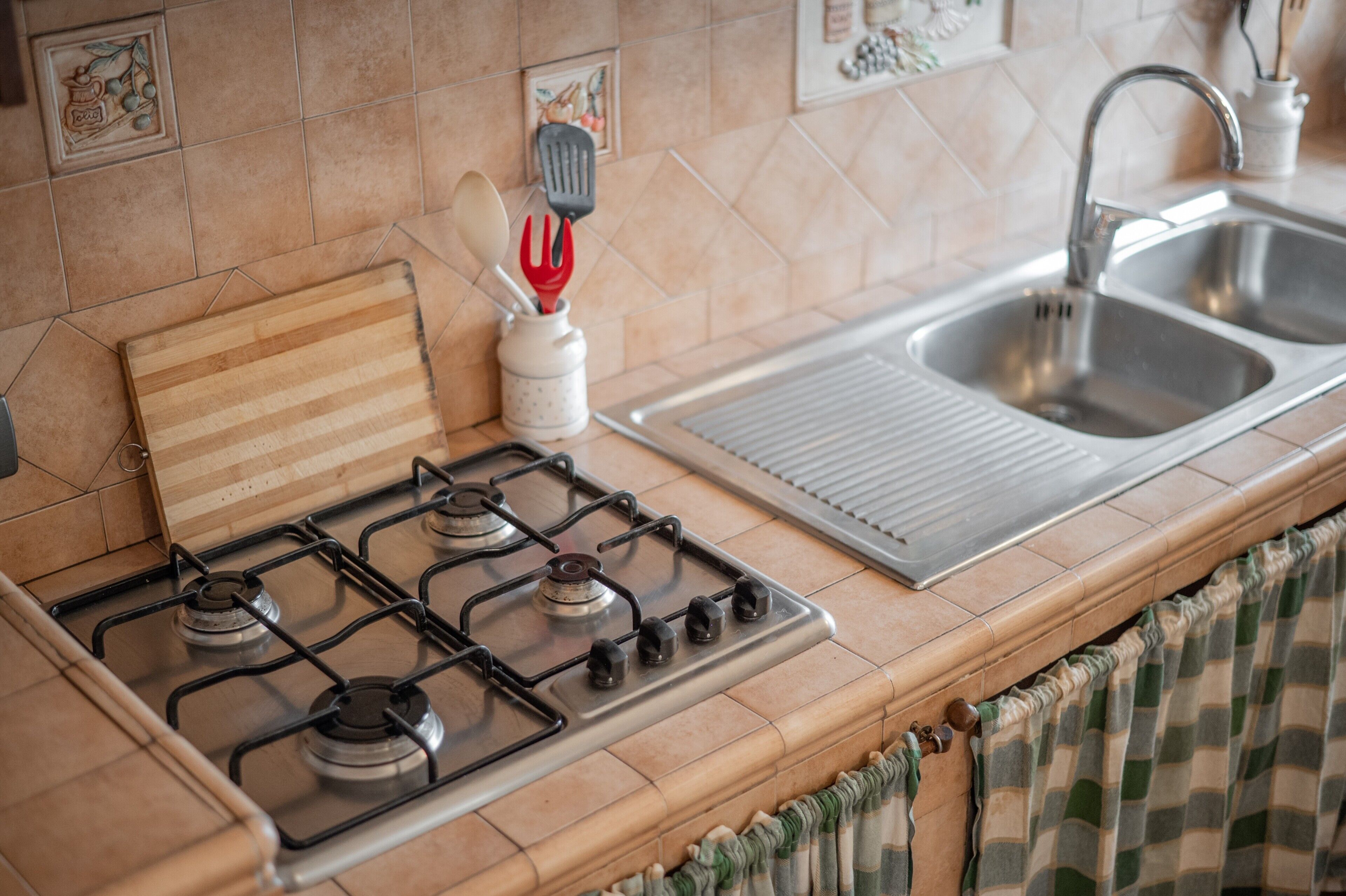A kitchen with a gas stove, a sink, and a tiled backsplash.