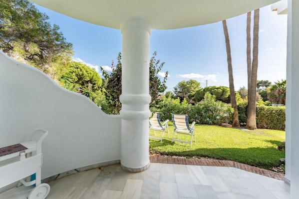 Un área de patio techada con un pilar blanco, una mesita y dos sillas.