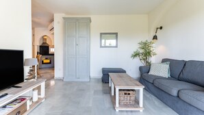 A modern living room with a grey sofa, a wooden coffee table, a TV, and a kitchen in the background. - Holiday Apartment "Casa Feliz" with Shared Pool, Private Terrace & Wi-Fi (Mijas)
