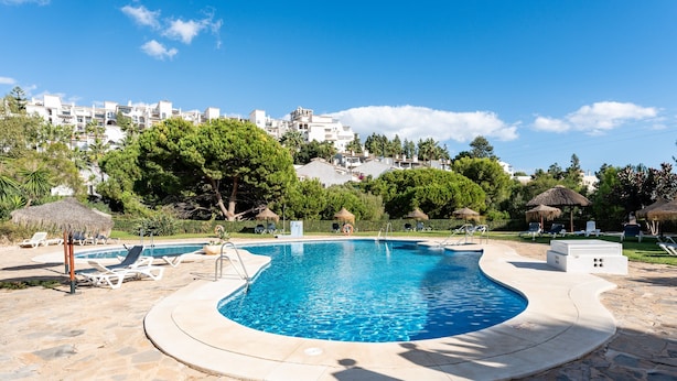 A swimming pool with lounge chairs, a stone deck, and a view of buildings in the background. - Holiday Apartment "Casa Feliz" with Shared Pool, Private Terrace & Wi-Fi (Mijas)