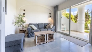 A modern living room with a grey sofa, a wooden coffee table, and a potted plant. - Holiday Apartment "Casa Feliz" with Shared Pool, Private Terrace & Wi-Fi (Mijas)