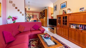 Ein Wohnzimmer mit einem roten Sofa, Holzschränken, einem Fernseher und einem Bücherregal.