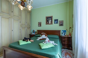 A bedroom with a bed, a dresser, a nightstand, and wall-mounted pictures.