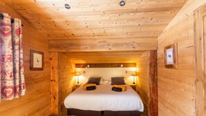 Ein Schlafzimmer in einer Holzhütte mit einem Bett, zwei Nachttischlampen und einem Fellteppich.