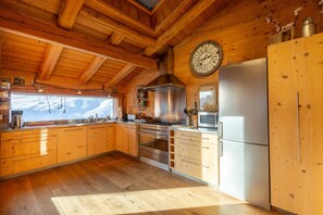 Une cuisine rustique aménagée dans une cabane en bois, avec un poêle, un réfrigérateur et des placards en bois.