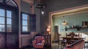 A room with a patterned armchair, a wooden table, and a chandelier. - Villa 'Il Frassine' with Private Pool, Wi-Fi and Air Conditioning (Rignano sull'Arno)