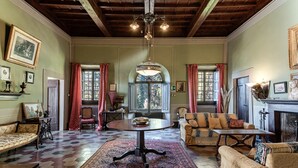 A traditional room with a wooden ceiling, a round table, a sofa set, and a fireplace. - Villa 'Il Frassine' with Private Pool, Wi-Fi and Air Conditioning (Rignano sull'Arno)