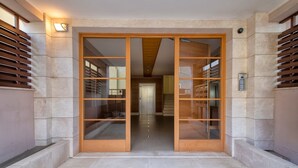 A modern building entrance with a glass door, a light fixture, and a security camera. - Holiday Home 'Villafranca' with Sea View, Wi-Fi and Air Conditioning (Alghero)
