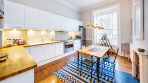 Une cuisine moderne avec des armoires blanches, un plan de travail en bois et un tapis à motifs bleus.