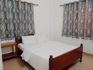 A single-bed room with a wooden frame, white bedding, a wooden nightstand, and curtains with a floral pattern. - Easy Go Home (Siem Reap)