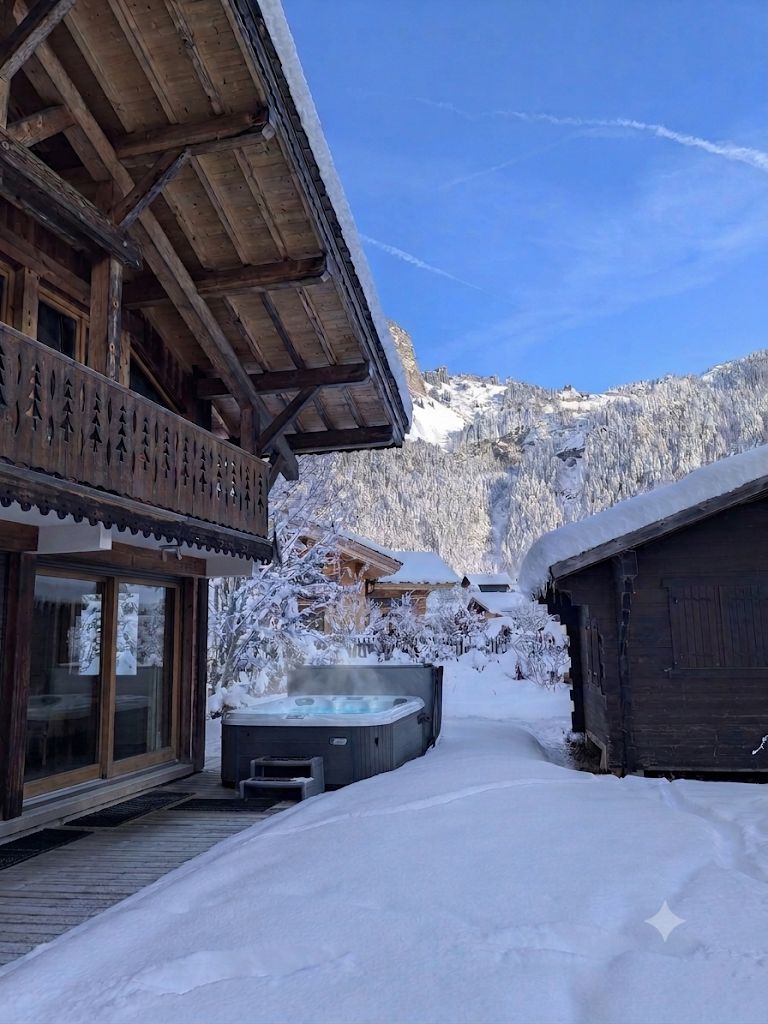 A wooden chalet with a hot tub in a snowy landscape.