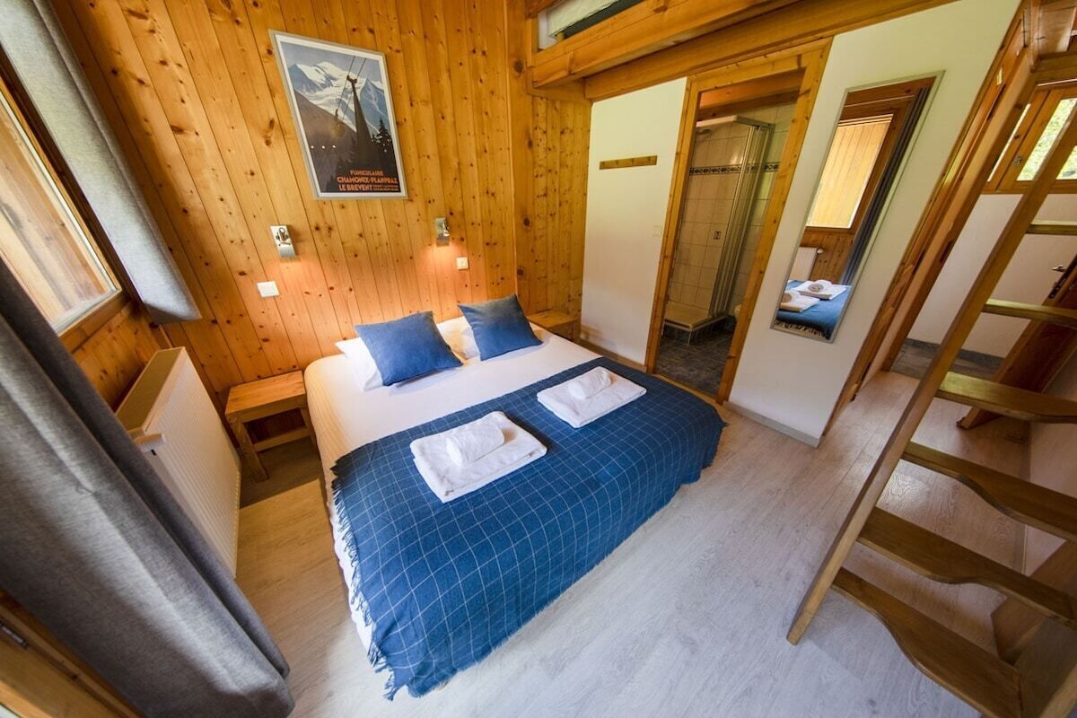 Ett sovrum med träpanel på väggarna, en säng, två sängbord, en spegel och en affisch på väggen.