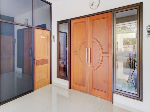 Un pasillo con una puerta de madera, una puerta de cristal y un reloj en la pared.