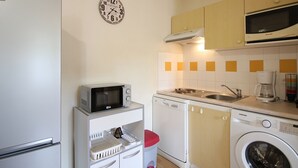 A compact kitchen with a microwave, dishwasher, and washing machine.