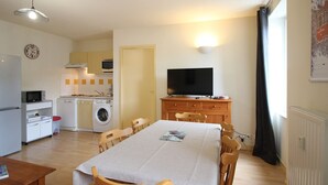 A compact living space with a dining area, kitchenette, and a television.