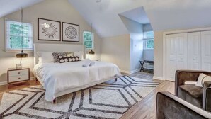 A bedroom with a bed, a ceiling fan, a nightstand, a desk, and a chair.
