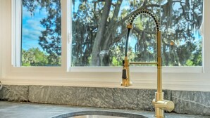 A kitchen with a stainless steel sink and a gold faucet.