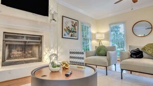 A modern living room with a fireplace, a round coffee table with decorative items, a sofa, and a chair.