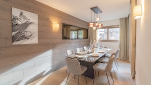 A dining area with a wooden wall, a large painting, and a table set for four.