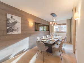 A dining area with a wooden wall, a large painting, and a table set for four.