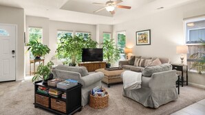 A spacious living room with a ceiling fan, a large flat-screen TV, a grey sofa, a coffee table, and a bookshelf. - A fresh new offering - Welcome to your Chico Getaway! (Chico)