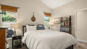 A bedroom with a large bed, a bookshelf, a window with blinds, and a wall-mounted sign. - A fresh new offering - Welcome to your Chico Getaway! (Chico)