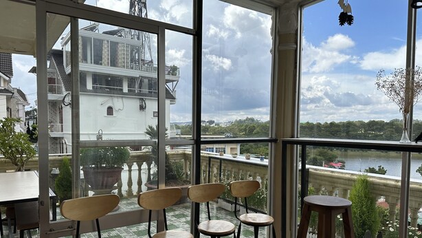 Un balcón con sillas y una mesa de madera, con vistas a un río y edificios históricos.