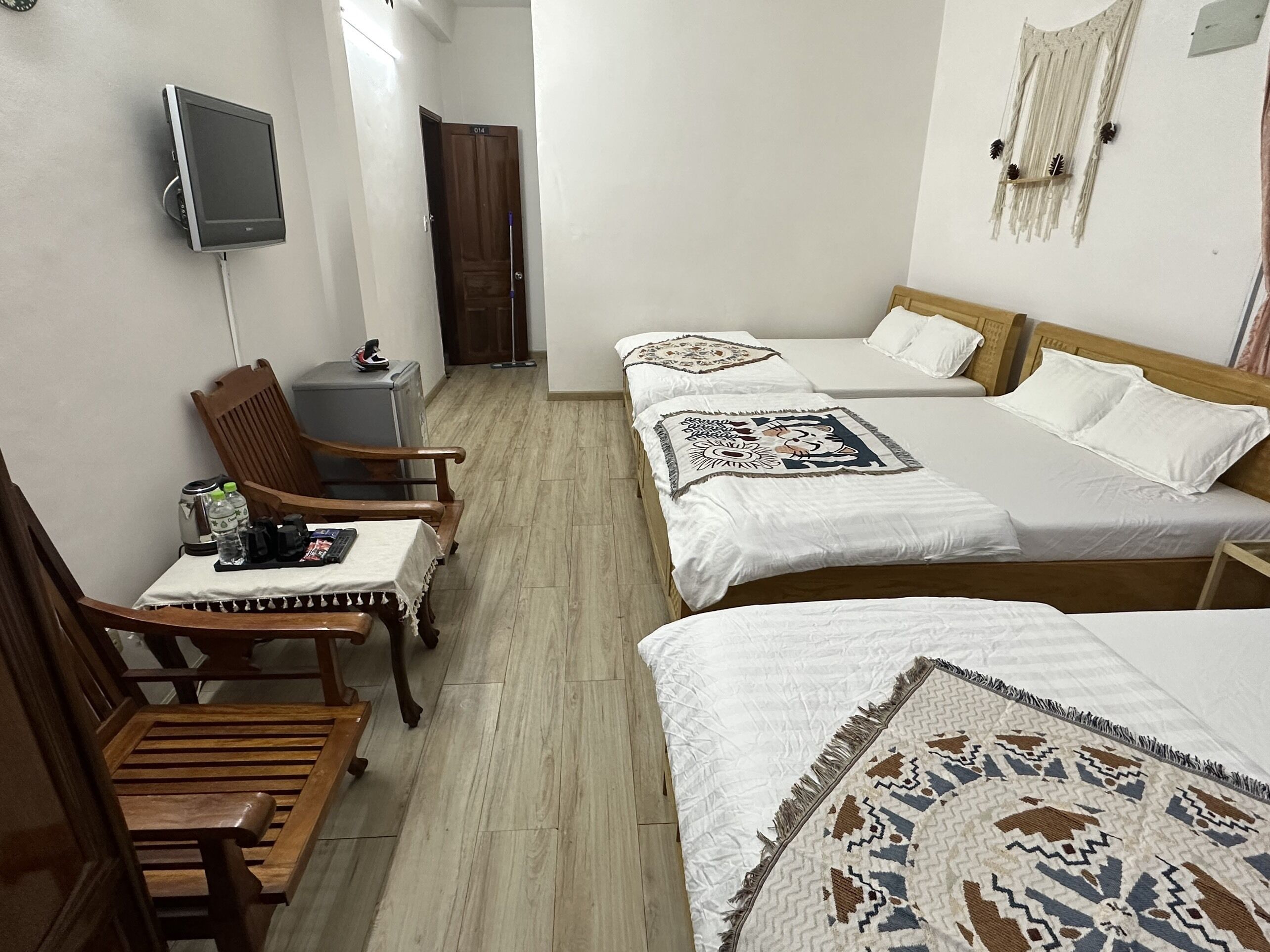 A hotel room with a desk, two beds, a TV, and a wall-mounted decoration.