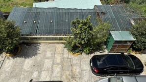 Un estacionamiento con dos coches, un edificio con techo verde y vegetación circundante.
