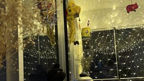 Una habitación con ventana, un osito de peluche, una lámpara y luces de cadena.