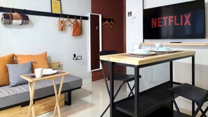 Een moderne woonkamer met een bank, salontafel, televisie en een eethoek met stoelen en een tafel.