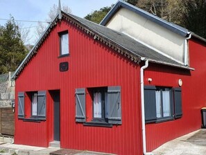 A red building with a gabled roof, a small window, and a door.
