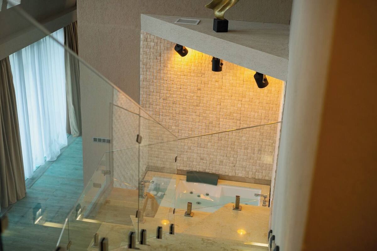 Un intérieur d’hôtel moderne avec un escalier en verre menant à un espace dédié aux soins et à la relaxation.